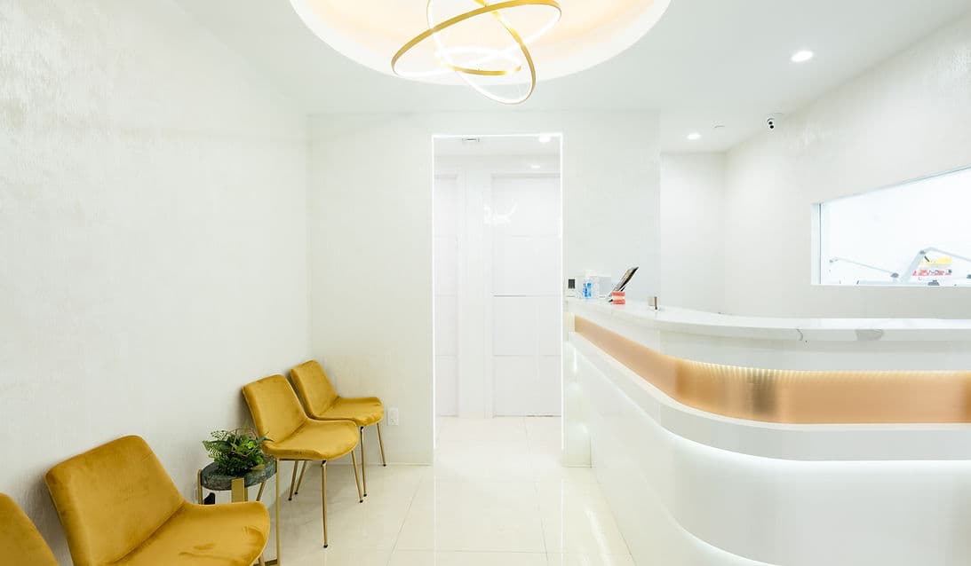 The reception area at Dream Smile Dental with yellow chairs and a curved white desk