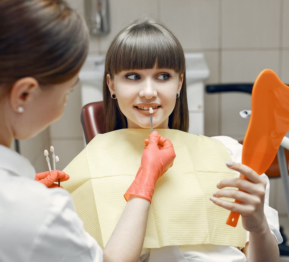 A dentist matching a veneer shade against a patient's teeth