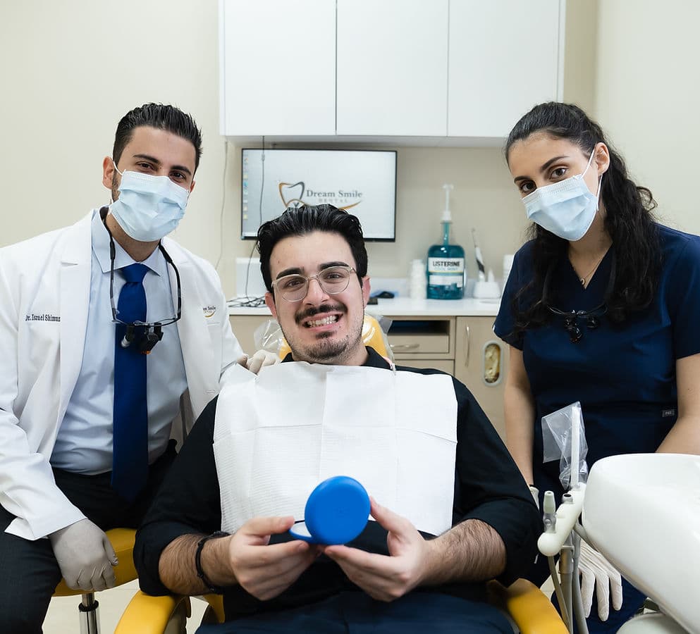 A Dream Smile Dental patient smiling while holding a clear Invisalign aligner