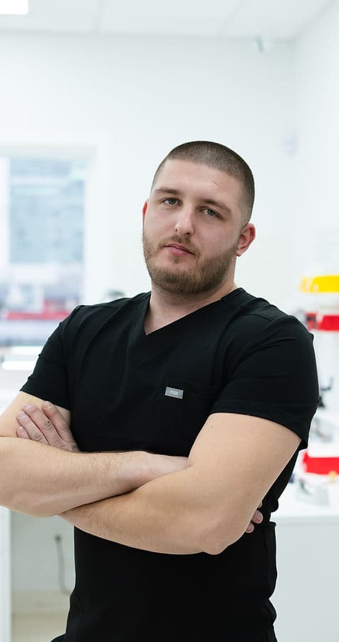 Almin, registered dental technician, arms crossed in the laboratory