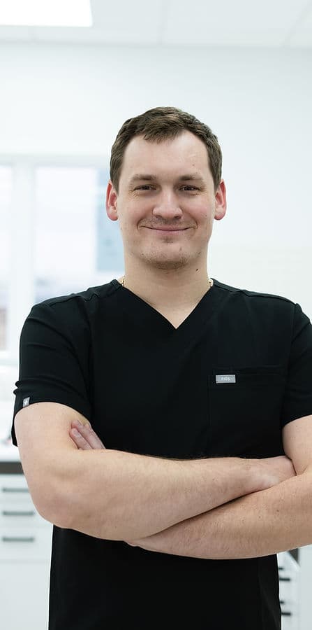 Dmitriy, registered dental technician, smiling with arms crossed